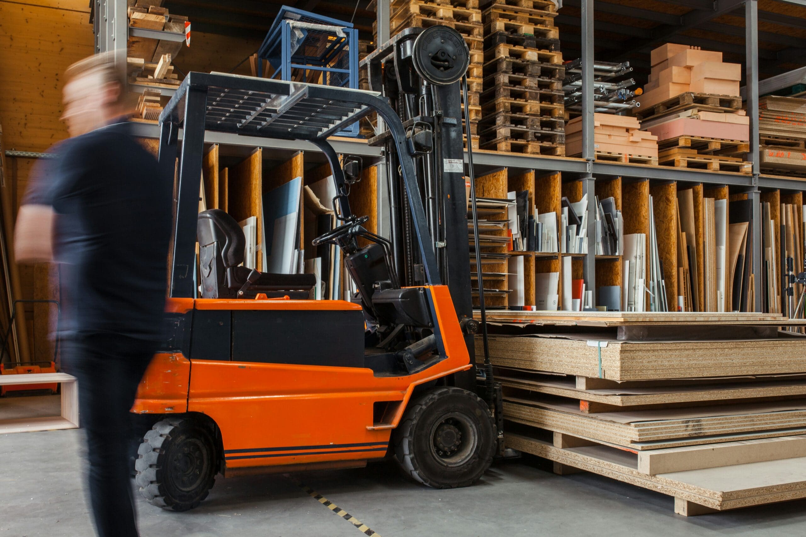 A futuristic warehouse interior showing a mix of human workers, autonomous mobile robots (AMRs), and advanced conveyor systems, all connected by glowing data lines representing a WMS.