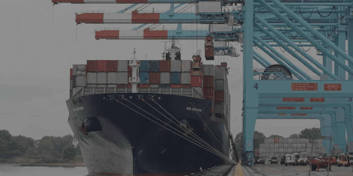 A large ship-to-shore crane at a busy U.S. port unloading shipping containers.