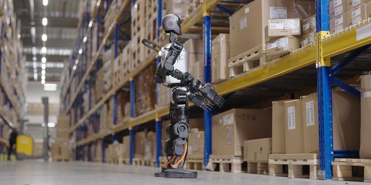A humanoid robot with its arms extended, standing in a warehouse aisle, with shelves of products visible in the background.