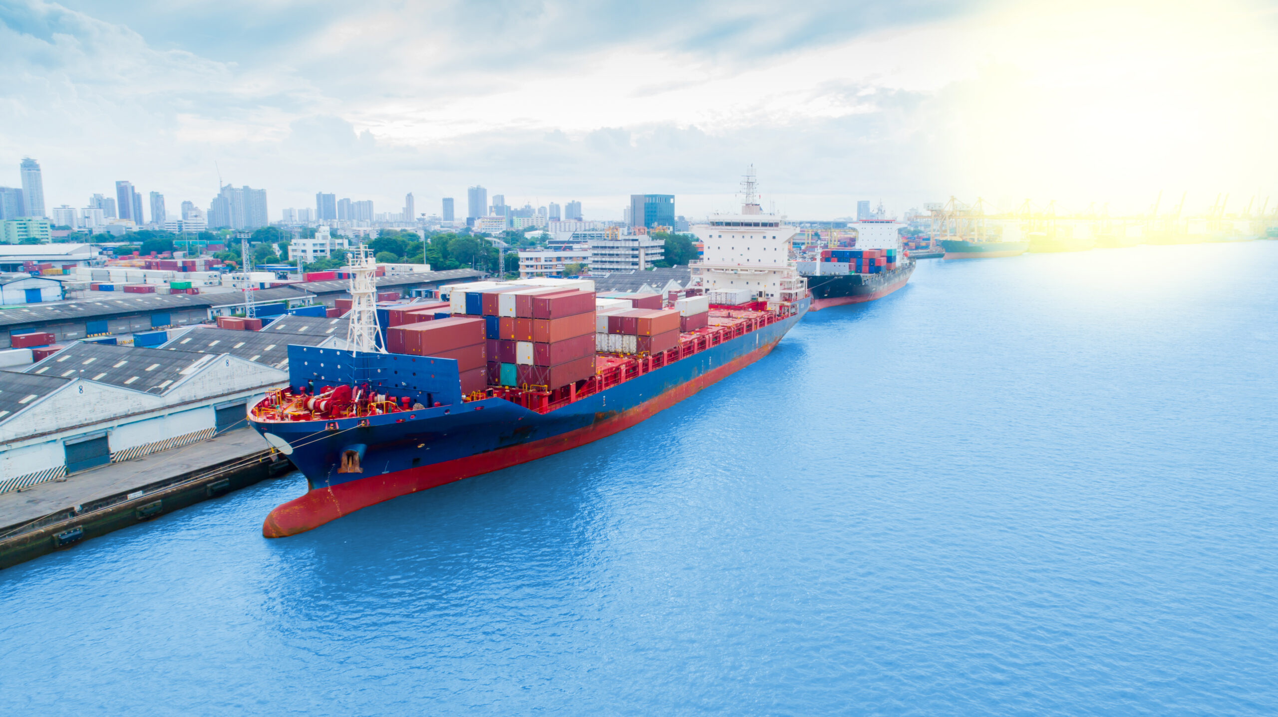 An illustration of a futuristic cargo ship with no visible crew on deck, sailing on a calm sea under a clear sky.