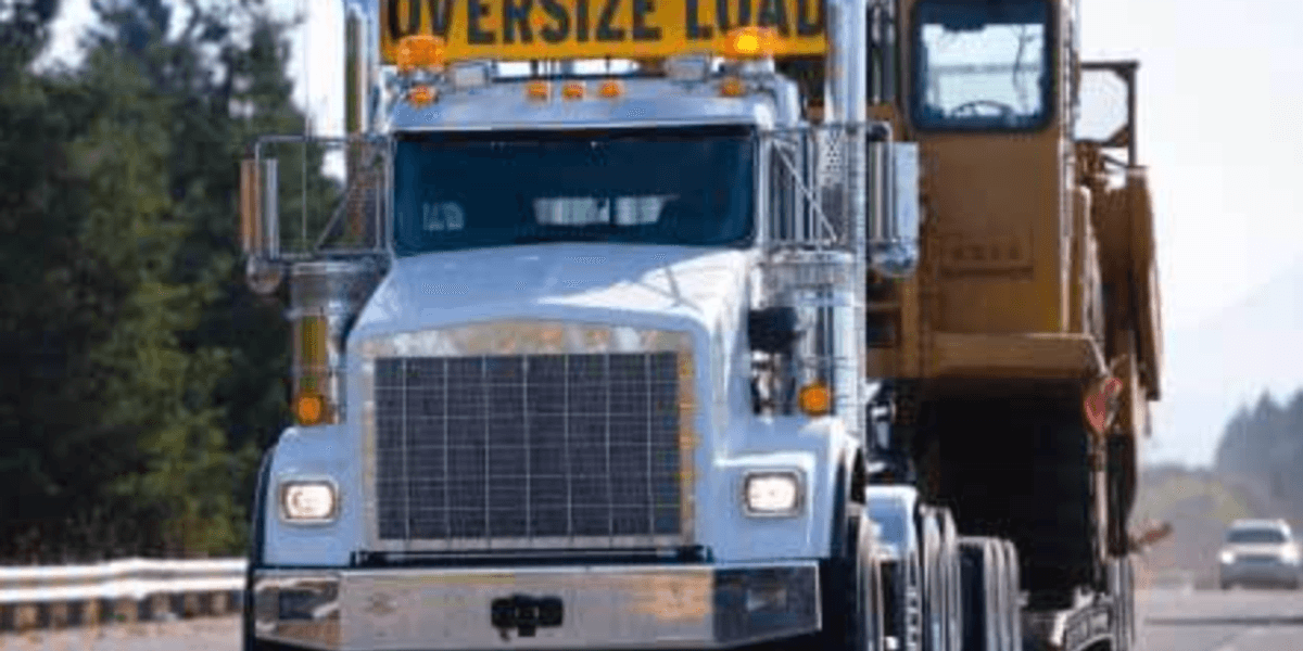 Truckstop.com logo overlaid on a heavy haul truck transporting oversized wind turbine blade