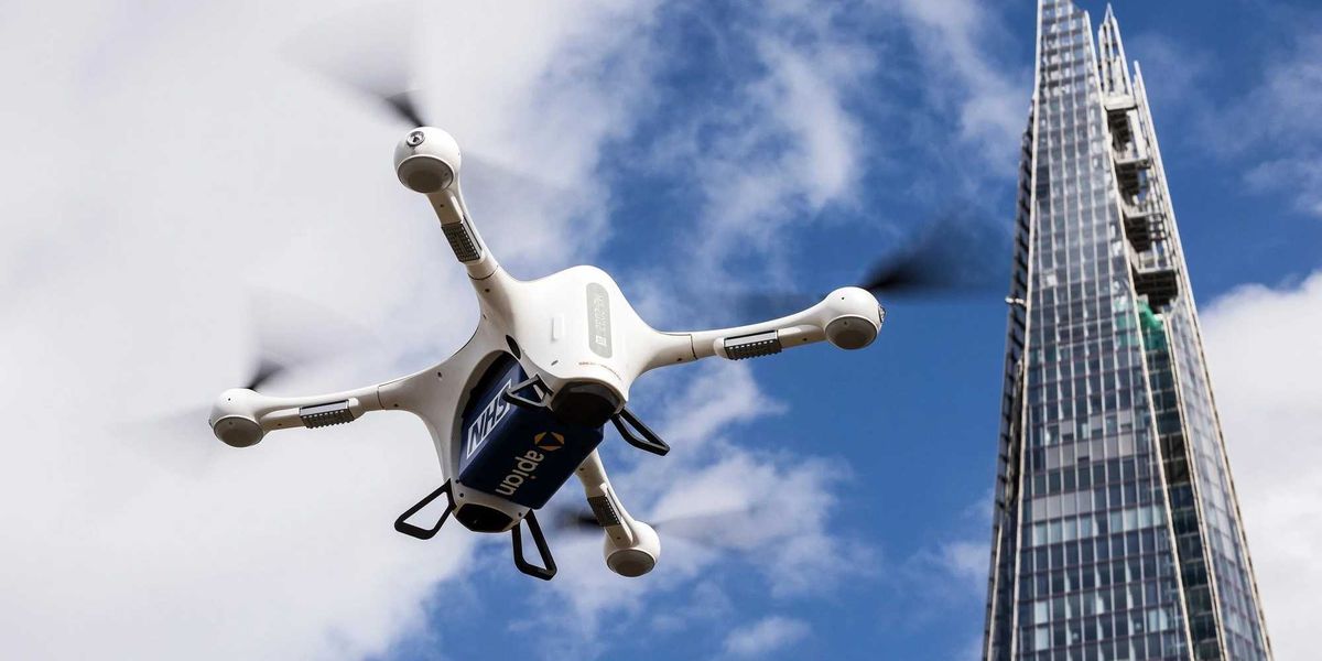 A Matternet M2 drone flying over the London skyline, carrying a small payload container.
