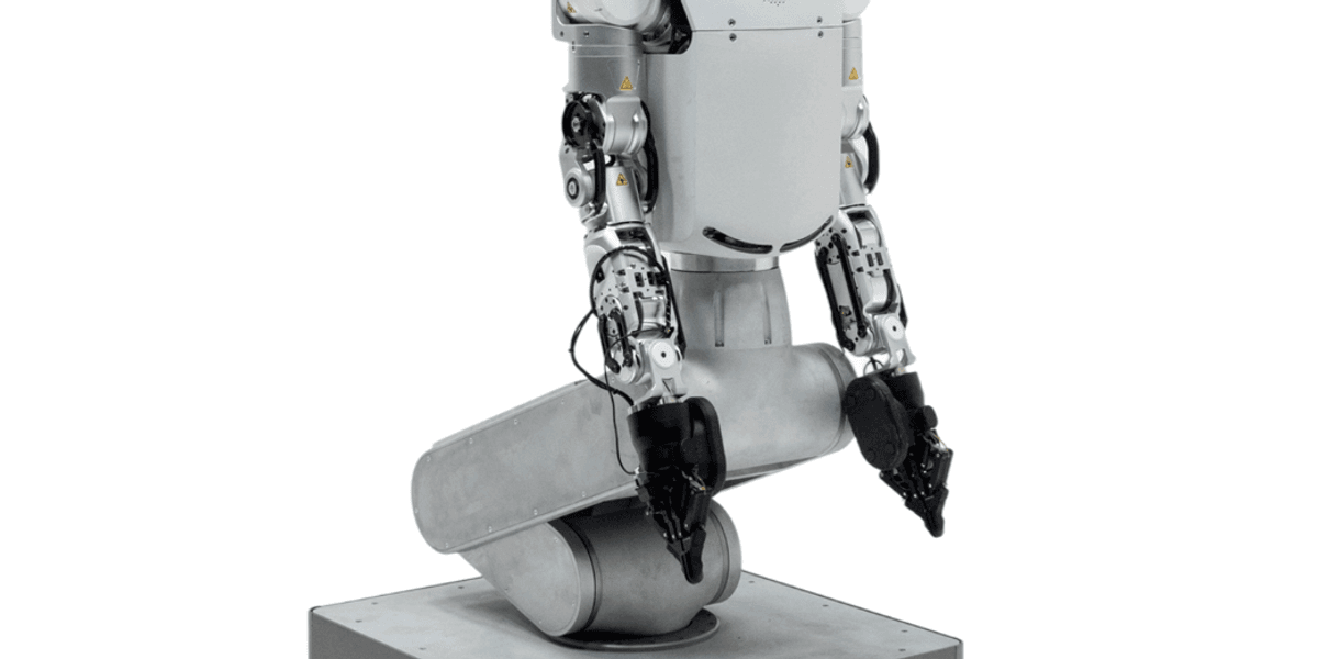 A humanoid robot with a human-like torso and arms operating in a factory setting
