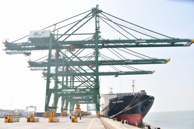 Container ships docked at a busy port with cranes and stacked containers visible.