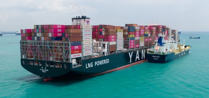 A container ship sailing on a rough sea under a dramatic sky.
