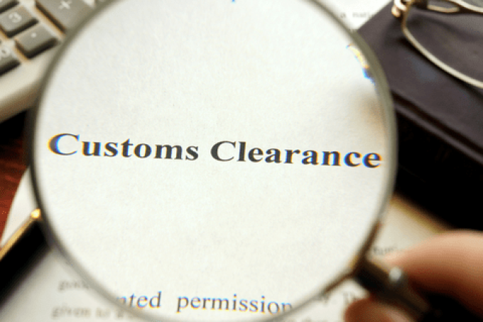 A person reviewing complex paperwork at a desk with a blurred background of shipping containers.