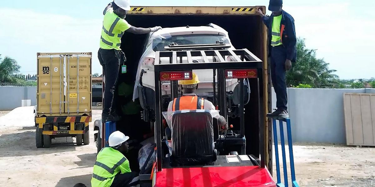 Workers assembling electric van kits from Chinese parts in Lagos factory, with refrigeration units visible