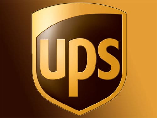 A UPS truck parked in front of a distribution center with a 'UPS' logo visible.