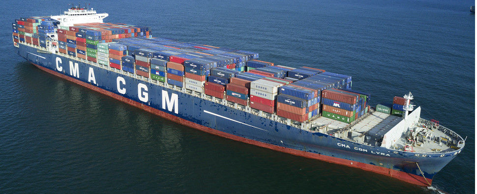 A large CMA CGM container ship sailing on the ocean under a blue sky.