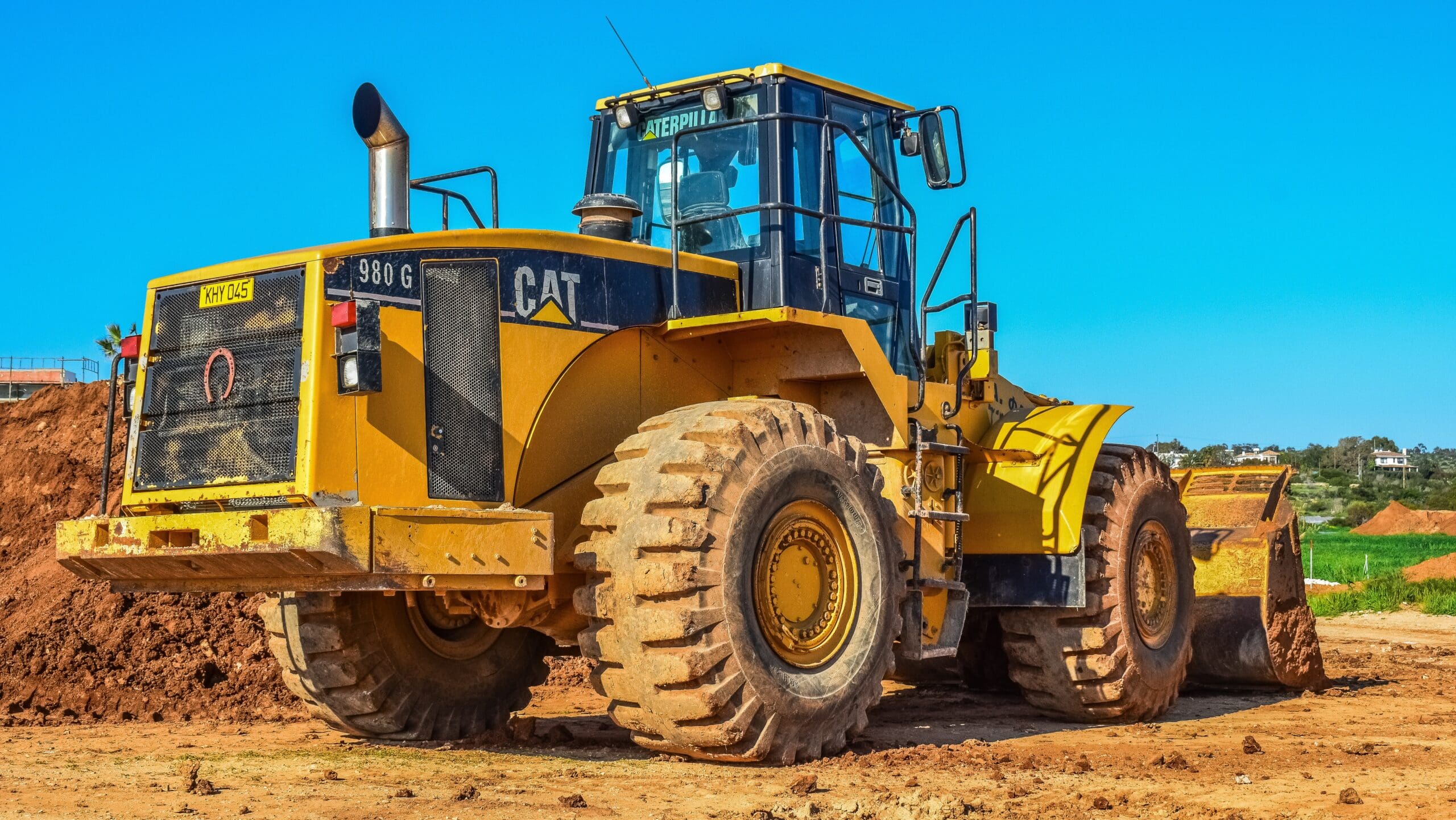 A yellow Caterpillar bulldozer digging at a construction site.