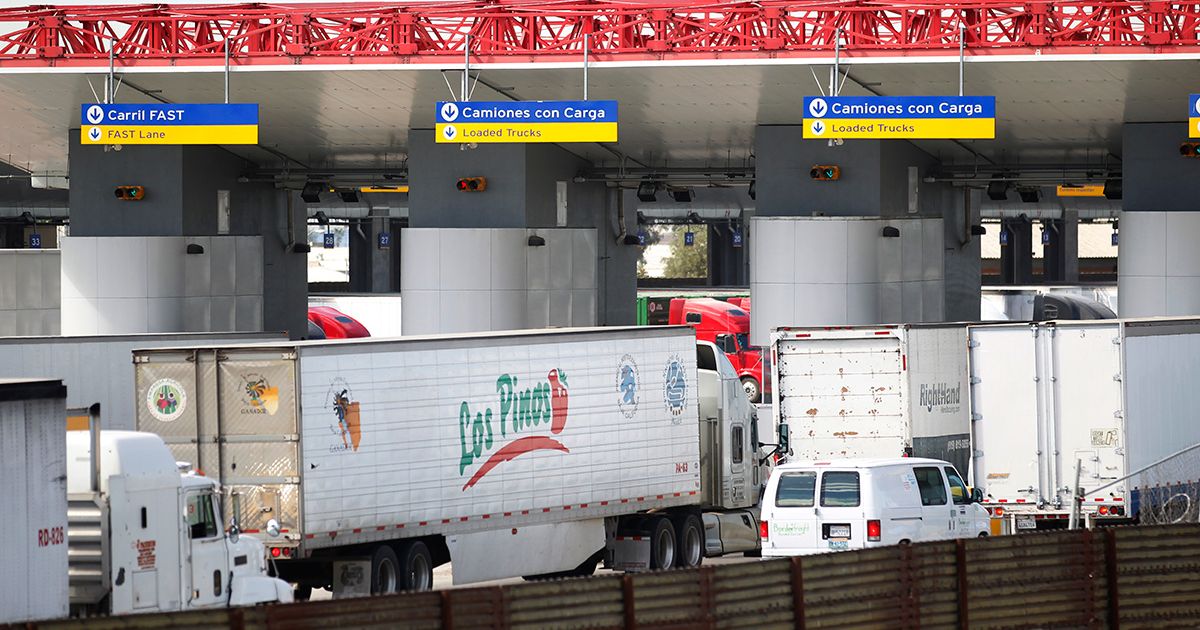 A U.S. Customs and Border Protection officer inspecting a commercial truck at a border crossing.