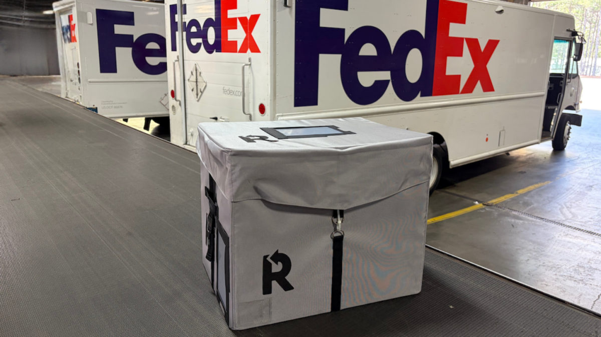 FedEx reusable blue packaging boxes stacked in a distribution center warehouse during pilot testing