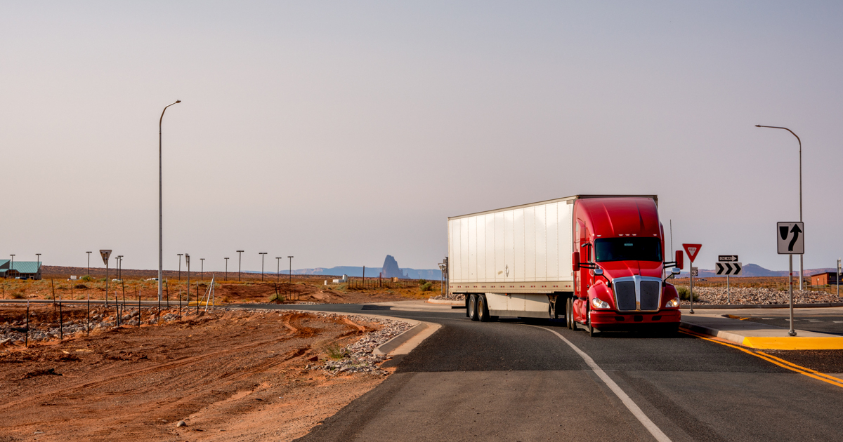 A semi-truck driving on a highway at sunset, symbolizing the movement of freight.