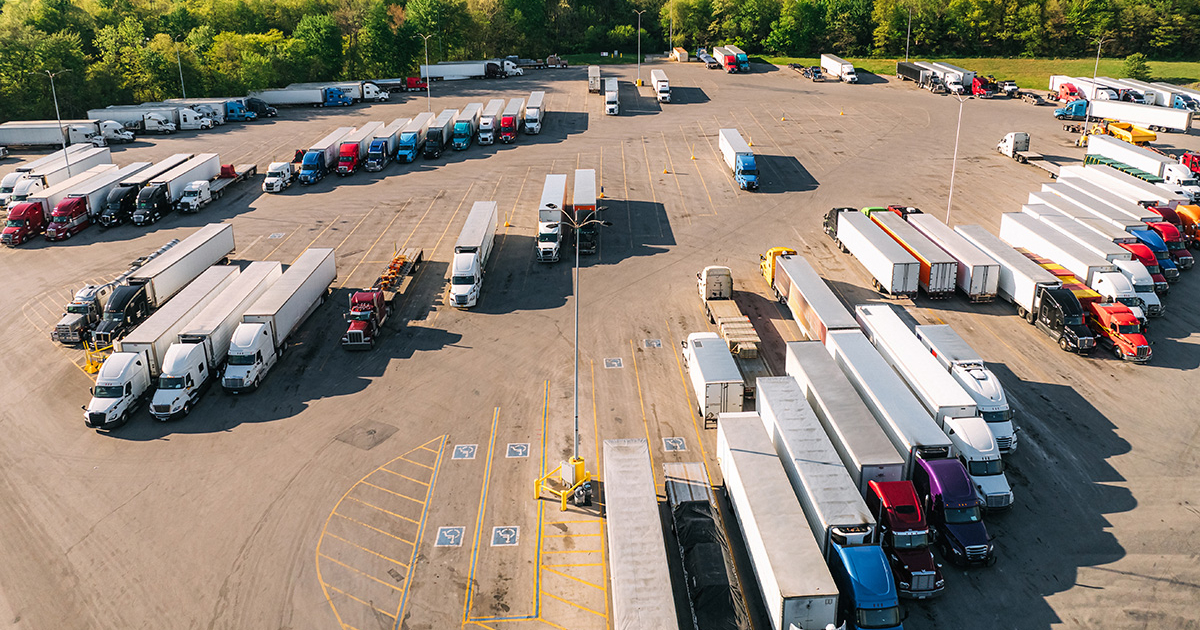 A semi-truck parked in a designated truck stop lot at sunset.