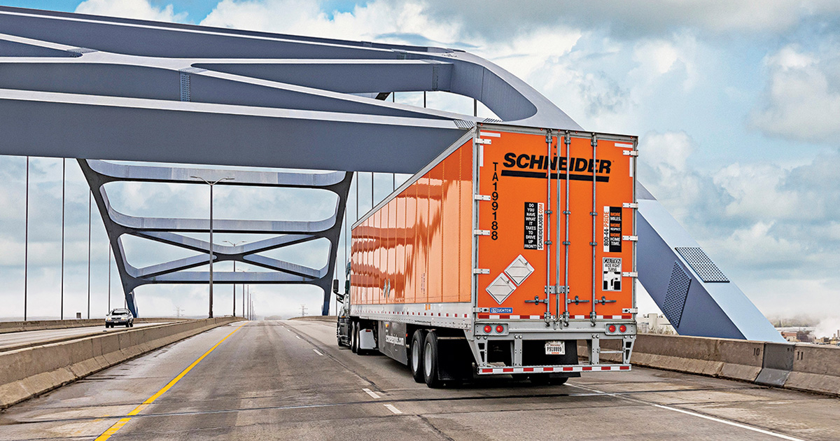Close-up of a Schneider truck driving on a highway at sunset.